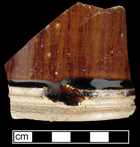 Manganese Mottled mug or tankard with cordoning at the foot band.  A break in the cordoning allowed the body glaze to run onto the unglazed cordoned area. The foot and base of the vessel are unglazed - collected by George L. Miller in 1986 in Staffordshire in Hanley.  Cannot be attributed to a specific pottery. 